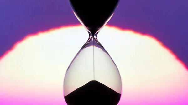 Hourglass on the background of a sunset. The value of time in life. time measuring tool. An eternity.