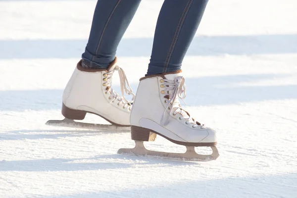 穿着蓝色牛仔裤 穿着白色溜冰鞋 站在冰球场上的女人的腿 业余爱好和休闲 冬季运动 — 图库照片