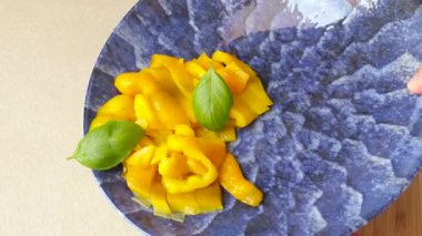 Mavi tabakta fesleğenli dilimlenmiş sarı biber. Yemek ve sağlıklı beslenme. Sebzeler ve diyet yiyecekler. Yüksek kalite 4k görüntü