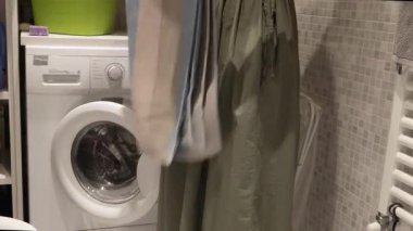 Çamaşırhanede havlu katlayan bir kadın. Çamaşır makinesi ve çamaşır dolabı. Temizlik ve yaşam tarzı. Olaylar, ev temizliği. Yüksek kalite 4k görüntü