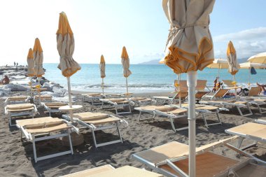 Plaj şemsiyeleri ve deniz kenarında güneşlenme yerleri. Yazın gün doğumu, İtalya, Liguria 'da tatil. Metin için arka plan. Yüksek kalite fotoğraf