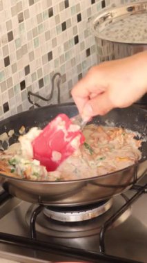 Kimliği belirsiz biri soğan ve kremayla Chanterelle kızartıp silikon spatulayla karıştırıyor. Mutfakta yemek ve yemek. Sağlıklı beslenme. - Evet. Yüksek kalite 4k görüntü