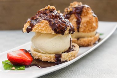 Beyaz bir tabakta dondurma ve çikolata ile taze profiteroles