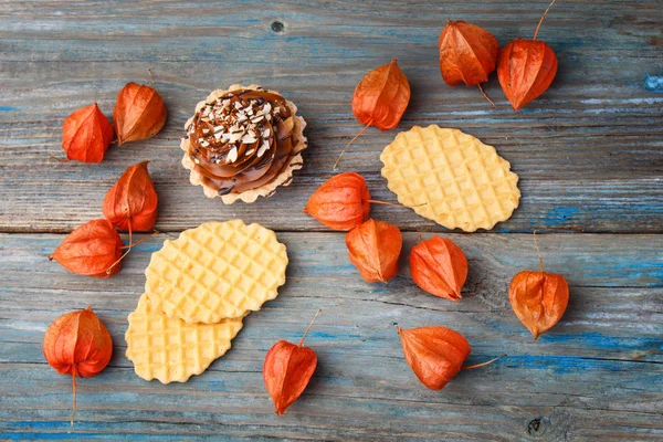 Gaufre sucrée, gâteau à la crème et physalis sur un backgr en bois — Photo