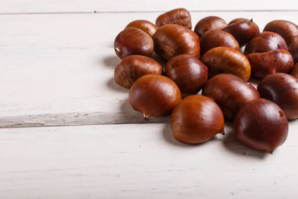 Stapel zoete kastanjes op witte houten achtergrond — Stockfoto