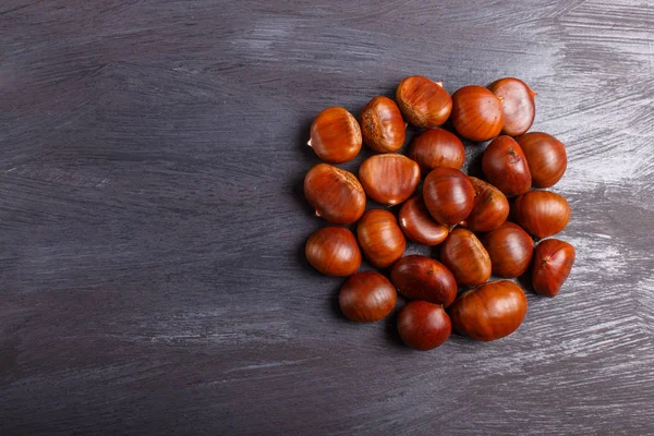 Pile of sweet chestnuts on black wooden background — Stock Photo, Image