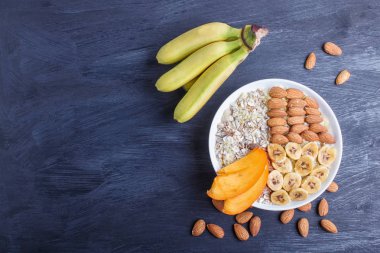 Müsli, badem, muz, siyah odunluk üzerine hurma ile bir tabak