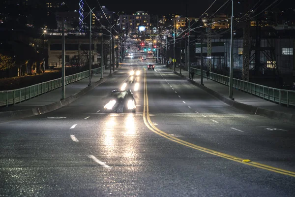 Looking down Jose Rizal Bridge road on dark evening with people commuting home from work