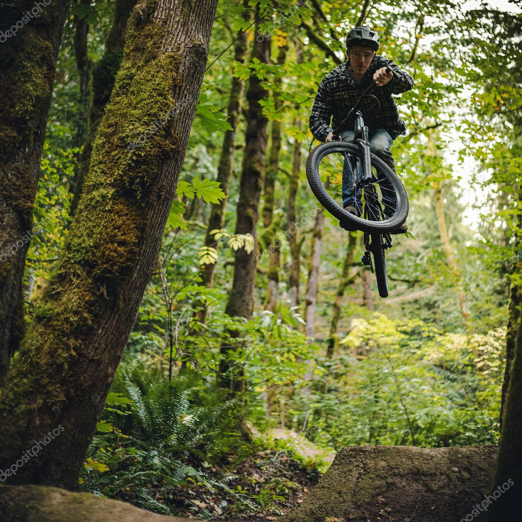 Hombre saltando alto en Dirt Mountain Bike saltar en el bosque