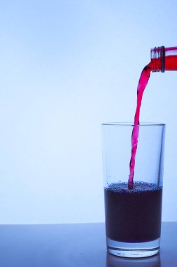 Kırmızı şarabı mavi bir bardağa doldur. Kaliteli fotoğraf