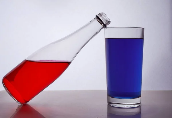 白い背景に多色の液体を持つボトルとガラスから構成されています 瓶はガラスの上にある 高品質の写真 — ストック写真