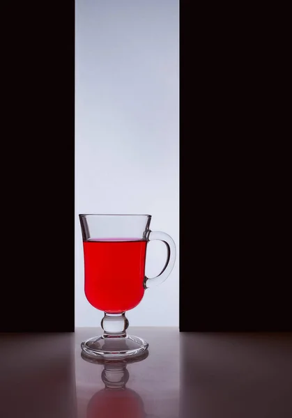 Vidrio rojo con líquido rojo sobre un fondo blanco negro. Foto con estilo —  Fotos de Stock