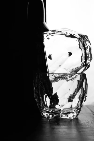 Een glas whiskey op elkaar liggen. Er staat een fles whisky. Zwart witte achtergrond. Silhouetten — Stockfoto