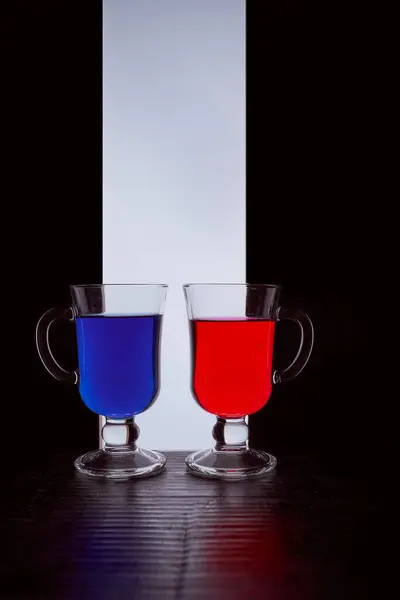 Siluety dvou brýlí na černobílém pozadí. Modrá a červená tekutina — Stock fotografie