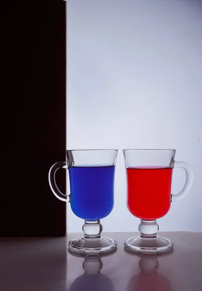 Siluetas de dos vasos sobre fondo blanco y negro. Líquido azul y rojo —  Fotos de Stock