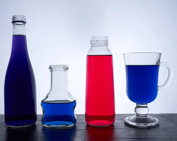 瓶装在浅蓝色和红色液体的底座上 — 图库照片