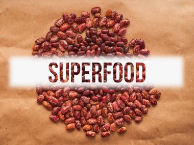 Kırmızı benekli fasulyeler kahverengi arka plana saçılmış. Dikdörtgen biçimi. Metin tasarımıyla. Yüksek kalite fotoğraf