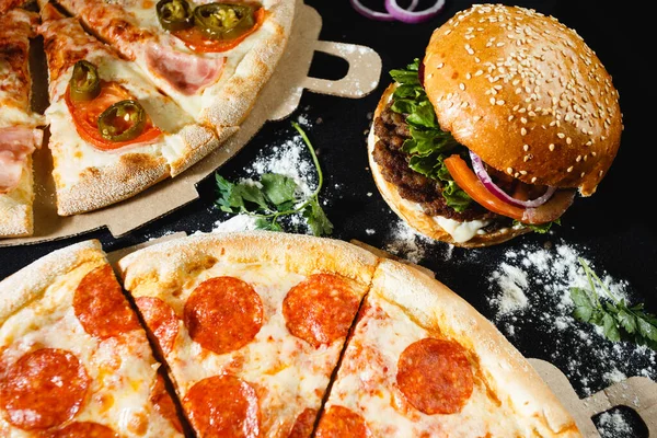 Pizza and burger on a black background. Top view. High quality photo