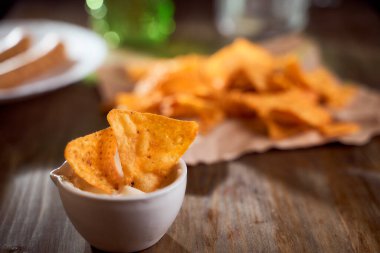 Tahta bir masanın üzerinde Meksika mısır cipsi var. Soslu bir kasede tek bir şey. Yüksek kalite fotoğraf