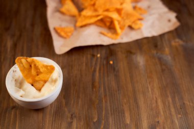 Tahta bir masanın üzerinde Meksika mısır cipsi var. Soslu bir kasede tek bir şey. Yüksek kalite fotoğraf