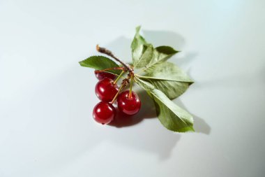 Beyaz arka planda mavi röfleli ve gölgeli bir kiraz. Yakın plan. Üst manzara, yüksek kalite fotoğraf.