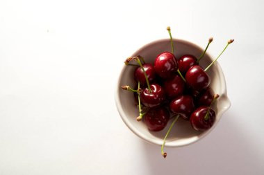 Beyaz arka planda gölgeli küçük bir fincanda bir grup kiraz. Yakın plan. Üst manzara, yüksek kalite fotoğraf.
