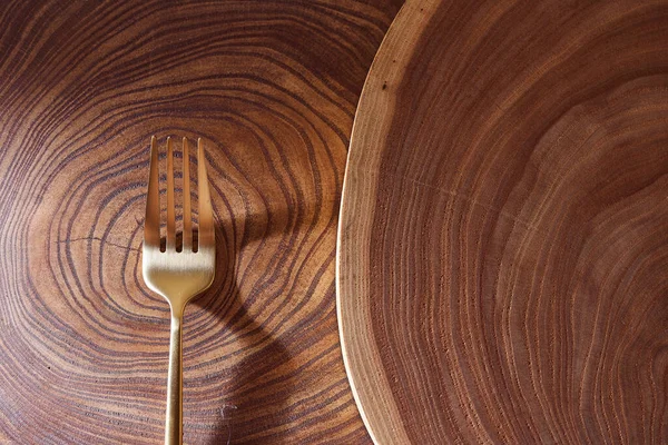 El tenedor de oro se encuentra en una rebanada de un árbol. Mesa de madera. Con espacio de copia . — Foto de Stock