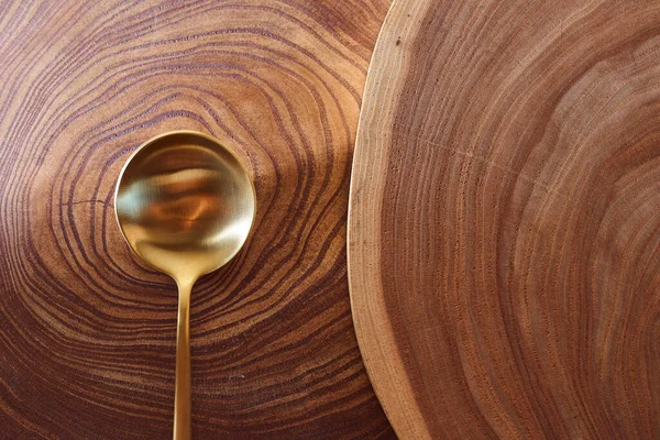 La cuchara dorada yace en una rebanada de un árbol. Mesa de madera. Con espacio de copia . — Foto de Stock