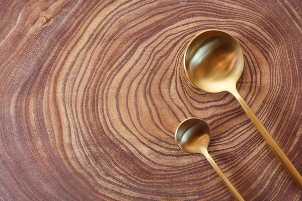 Las cucharas doradas se encuentran en una rebanada de un árbol. Mesa de madera. Con espacio de copia . — Foto de Stock