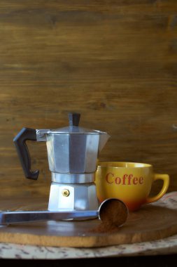 Ahşap tepside gayzer kahve makinesi. Yanında da bir fincan kahve var. Karanlık arka plan. Yüksek kalite fotoğraf