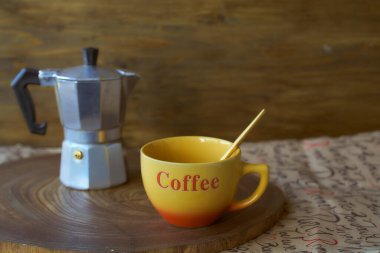 Ahşap tepside gayzer kahve makinesi. Yanında da bir fincan kahve var. Koyu arkaplan