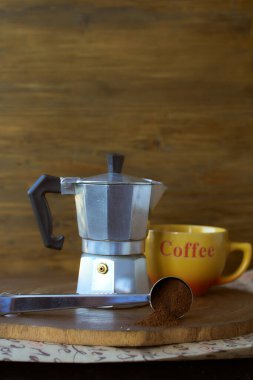Ahşap tepside gayzer kahve makinesi. Yanında da bir fincan kahve var. Koyu arkaplan