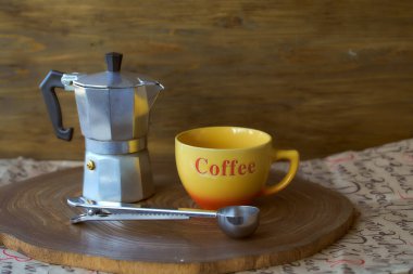 Ahşap tepside gayzer kahve makinesi. Yanında da bir fincan kahve var. Koyu arkaplan