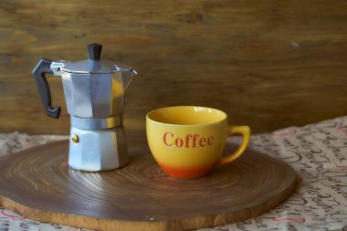 Ahşap tepside gayzer kahve makinesi. Yanında da bir fincan kahve var. Koyu arkaplan