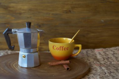 Ahşap tepside gayzer kahve makinesi. Yanında da bir fincan kahve var. Karanlık arka plan. Kopyalama alanı ile.