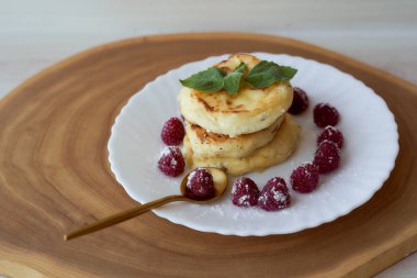 Meyveli peynirli kekler beyaz bir çay tabağının üzerinde ahududu ve nane yaprağı ile yatar. Hafif arkaplan. Yüksek kalite fotoğraf