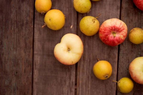 Kırmızı elmalar ve küçük armut tahta bir tahtanın üzerinde yatıyor. En iyi görüntü. Kopya alanı da var. Yüksek kalite fotoğraf