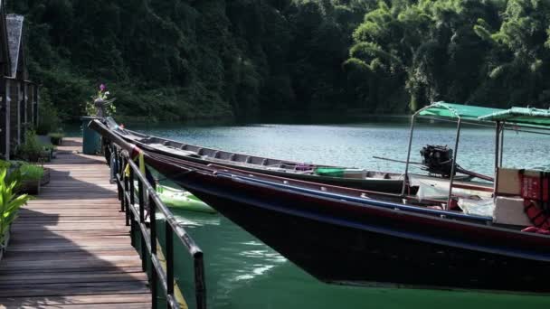 Соломенный дом на крыше у озера. Лодка, привязанная к причалу, рыщет на волнах, озеро Чоу-Лан. Национальный парк Као Сок. Таиланд . — стоковое видео
