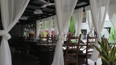 Khao Sok-Kasım 22. Sokakta boş bir restoran veya kafe, Rüzgar beyaz perdeler sallanan, bir fan tavana dönüyor, kahverengi ahşap sandalyeler masalarda bulunmaktadır. Kasım 22, 2018 içinde