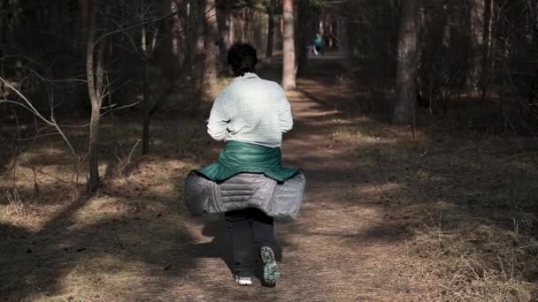 Een vrouw loopt over ruw terrein in een park bos. Hardloop motivatie in een groen park inspirerend landschap. Loop een marathon door het bos. Slow Motion — Stockvideo