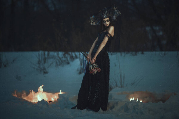 Beautiful model wearing black dress is posing on a snow