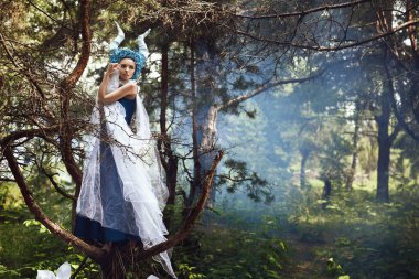 Güzel model mavi boynuzları olan bir ormandaki poz