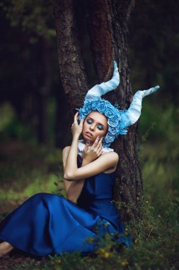 Güzel model mavi boynuzları olan bir ormandaki poz