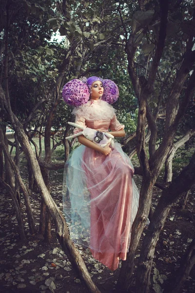 Beautiful model wearing pink dress is posing in a creative wig