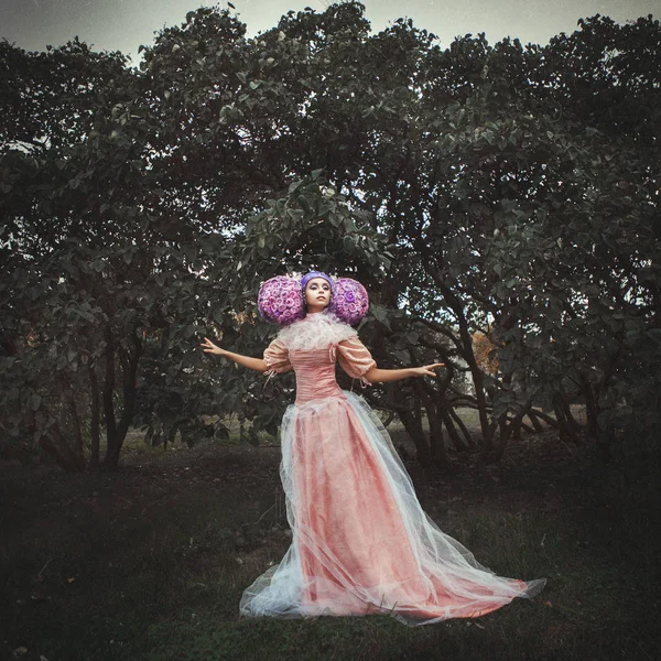 Beautiful model wearing pink dress is posing in a creative wig