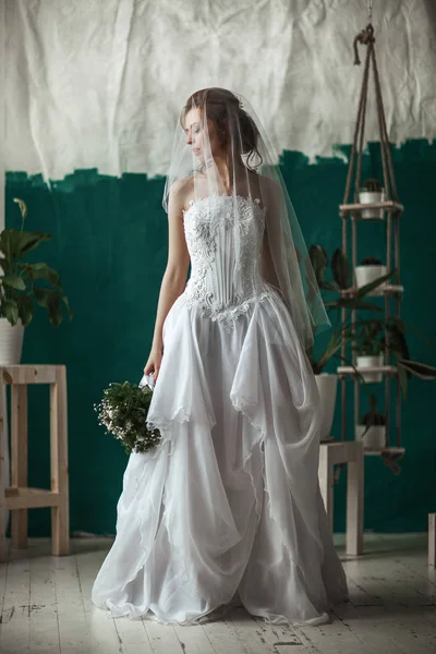 白いウェディング ドレスを着ている美しいモデルは内部のスタジオでポーズをとってください — ストック写真