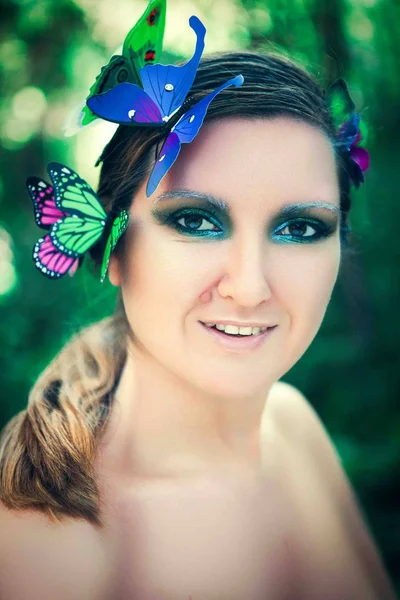 Model is posing with butterflies on her face