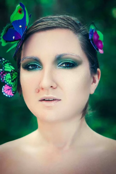 Model is posing with butterflies on her face