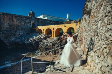 Beyaz elbise giyen güzel manken denizin yanında poz