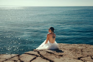 Beyaz elbise giyen güzel manken denizin yanında poz